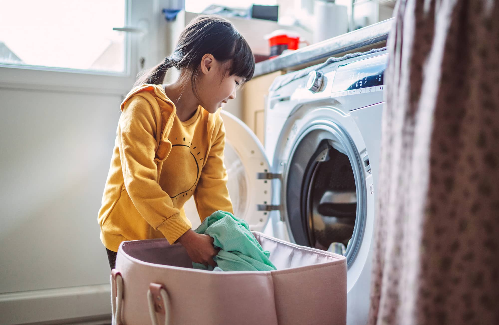 Shop for laundry room essentials, showing a small girl loading a washer 