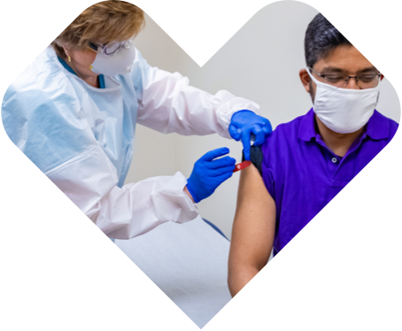 Vacunador de CVS Health coloca un apósito en el brazo de un hombre después de vacunarlo.