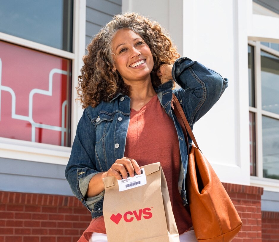 Mujer sale de tienda CVS con bolsa de pedido para recoger de CVS.