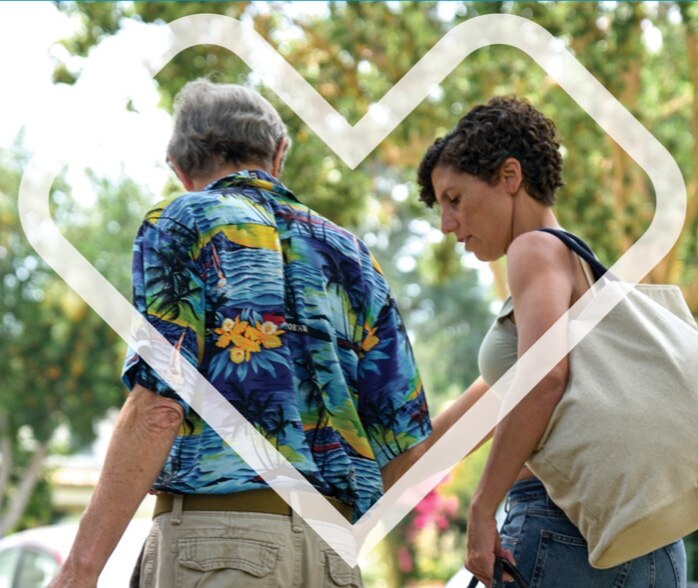 Man and woman with shopping tote bag are walking outdoors.