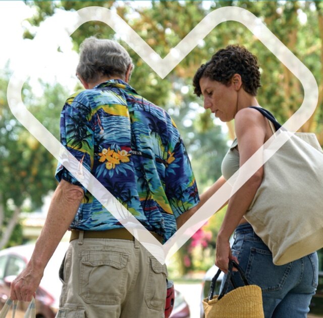 Man and woman with shopping tote bag are walking outdoors.