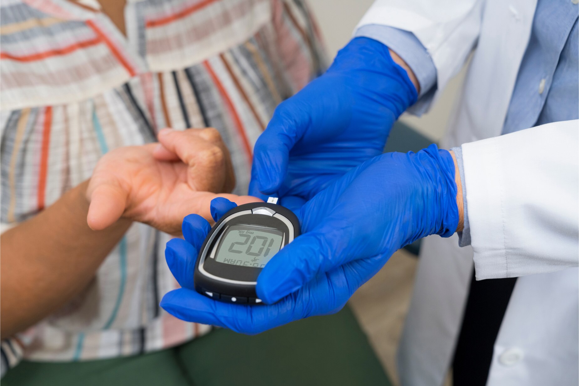 Un proveedor de MinuteClinic usando un glucómetro para leer la glucosa en sangre de un paciente en un entorno clínico.