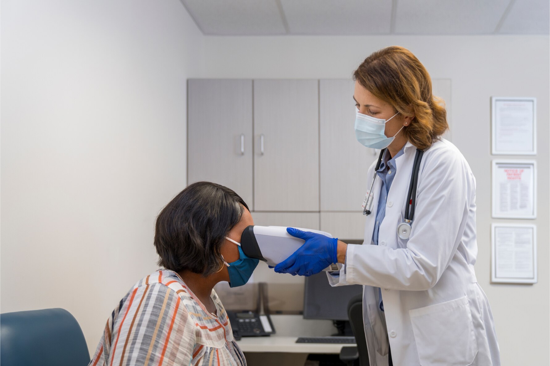 A MinuteClinic provider performing a diabetic retinopathy exam on her patient in a clinical setting.