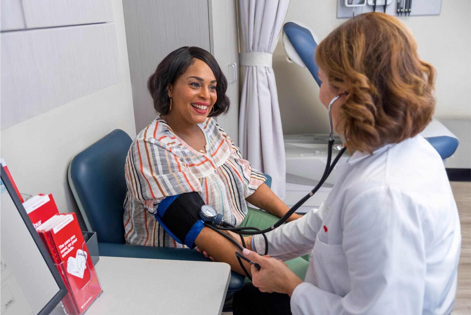 A patient is having her blood pressure taken by a MinuteClinic provider in a clinical setting.