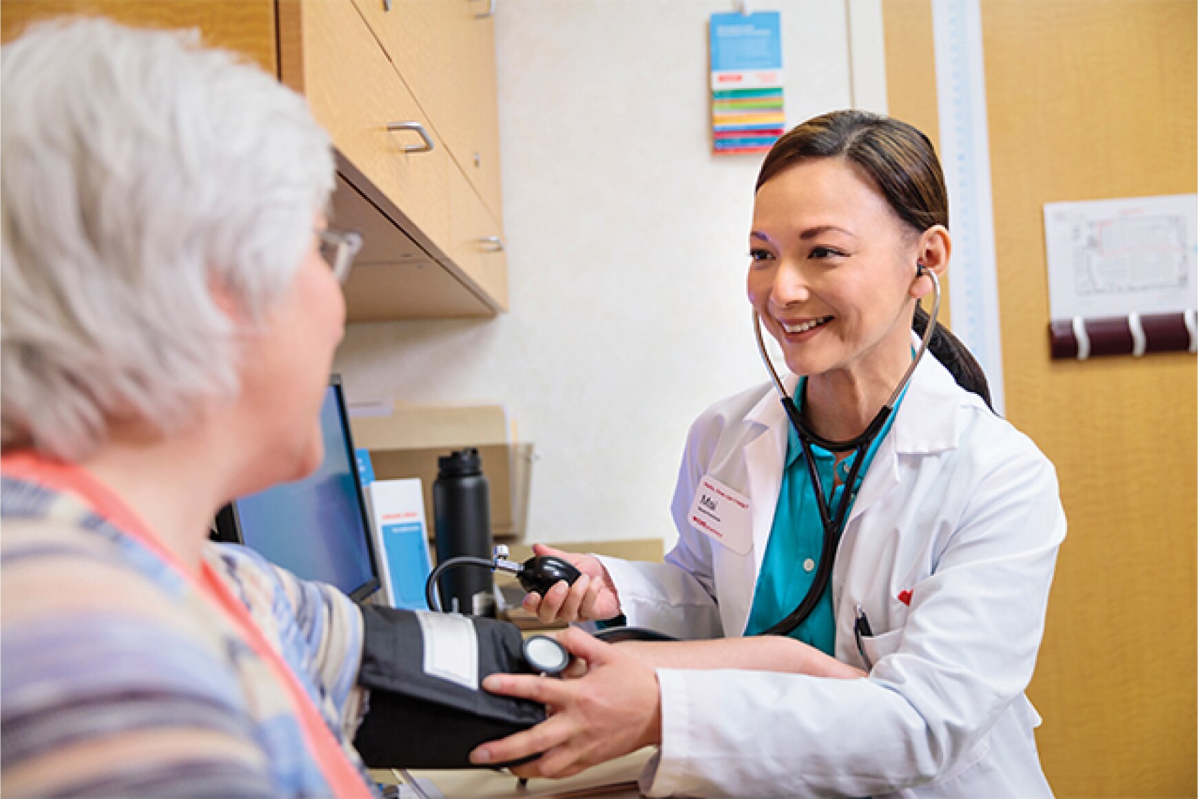 An older patient is having her blood pressure taken by a MinuteClinic provider in a clinical setting.