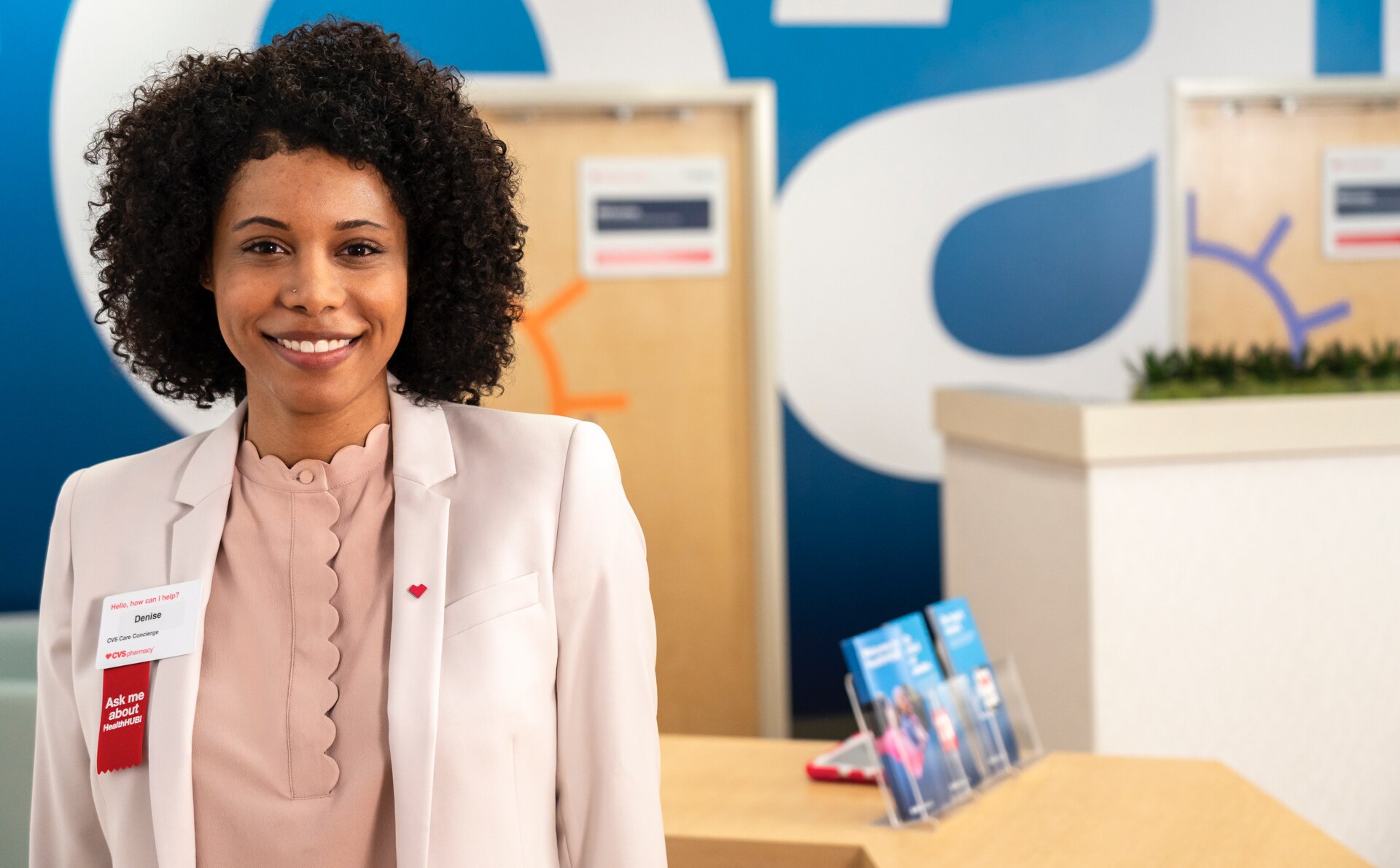 Empleado de la Farmacia CVS sonriente, listo para contestar preguntas en HealthHUB.