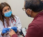 A health practitioner screens a patient for chronic conditions.