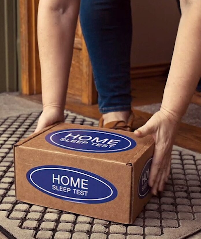 A person picks up a delivered home sleep test from their door step.