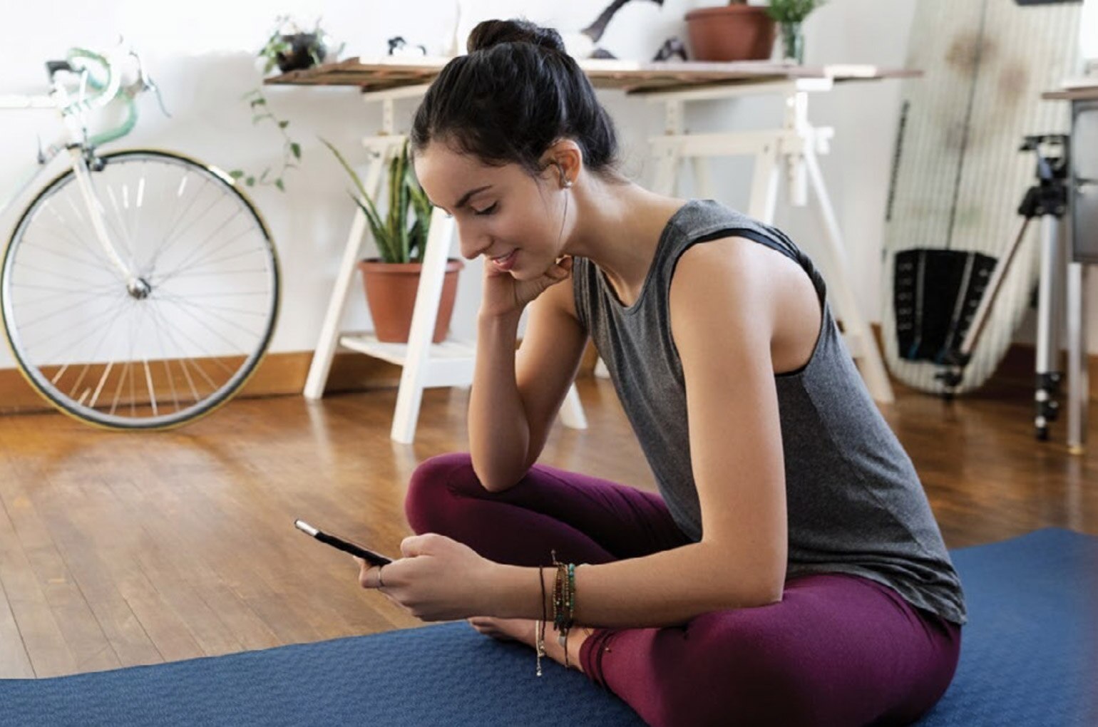 Inside her living room, a woman manages her prescriptions using the CVS app after a workout.