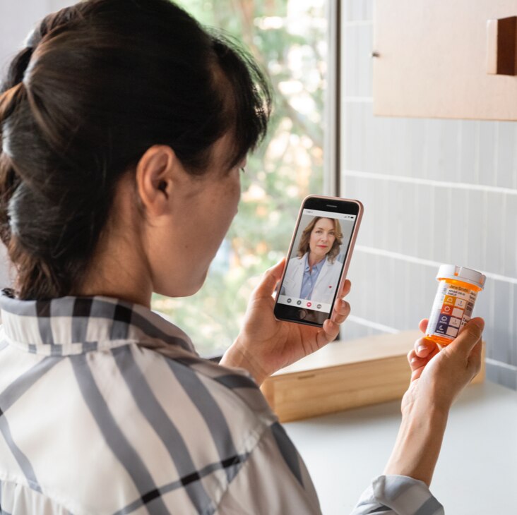 Mujer sentada en un sofá interactuando con un profesional de la salud en una tablet durante una consulta de telesalud. Conozca más sobre MinuteClinic ahora.