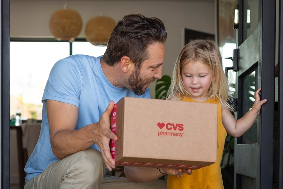 Imagen de hombre con niña sosteniendo una caja de entrega de CVS.