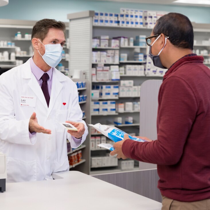 Farmacéutico de CVS hablando con un cliente retirando medicamentos recetados.