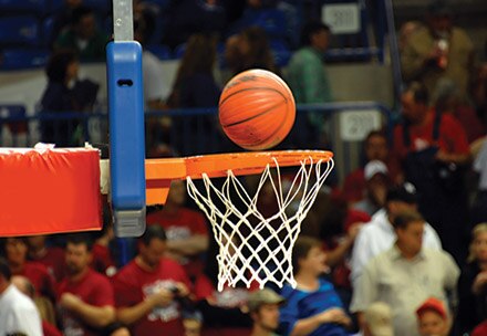 A basketball enters a hoop at a live game.