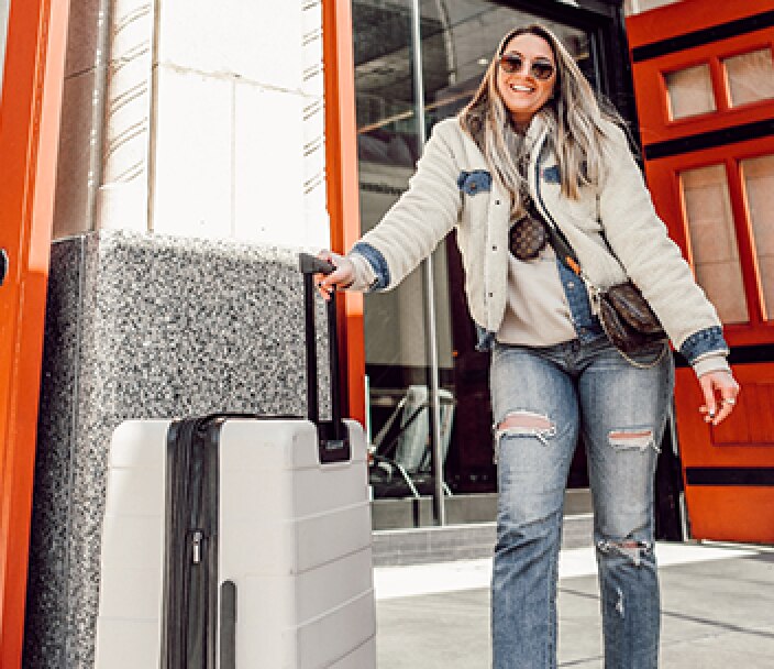 Instagram Influencer @sarakauten smiling with her luggage outside of her local CVS Pharmacy.