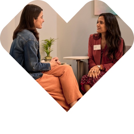 The CVS heart shaped logo containing an image of a young woman talking with her therapist in a medical office.