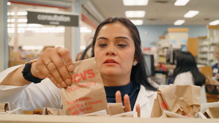 Grishma, a pharmacy manager, reviews the label on a bag of prescriptions that is ready for pickup.