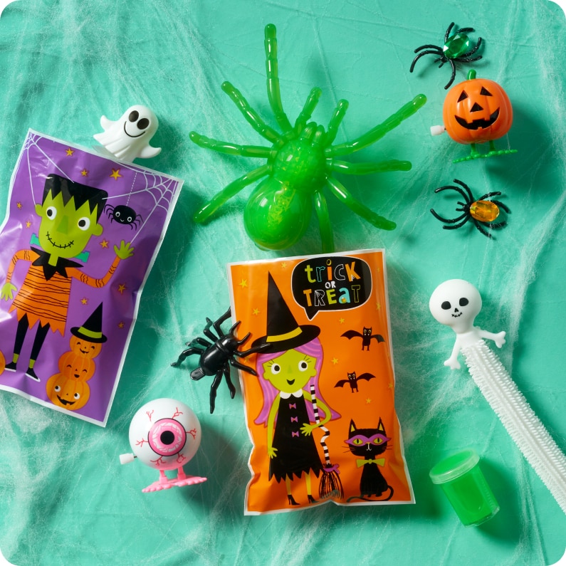 Halloween themed toys and trinkets rest on cobwebs, including windup eye balls, ghost figurines, spider rings and goody bags.