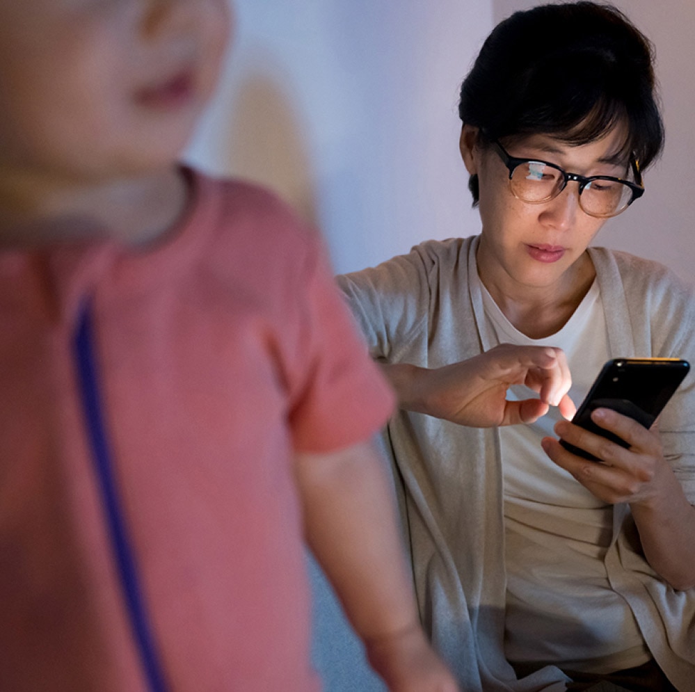 Mother concerningly scrolling her cellphone while watching her toddler.