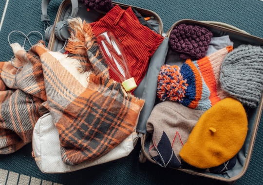 A suitcase sits open with clothes and travel essentials in it.