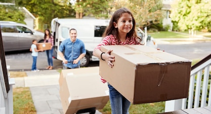 A family moves boxes from a moving a van into their new home.
