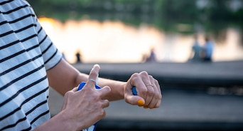 A person applies spray-on bug repellent to their exposed arms.