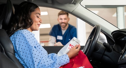 A person picks up their prescriptions at the drive-through line at CVS.