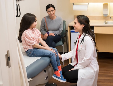 A MinuteClinic practitioner speaks with a child before an exam.