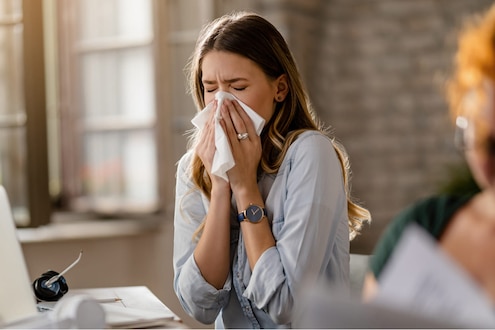 A person sneezes into a tissue.