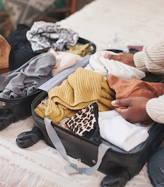A person packs a suitcase.