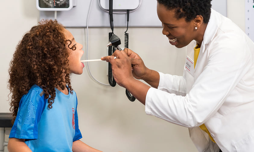 A MinuteClinic provider examines a child's mouth.