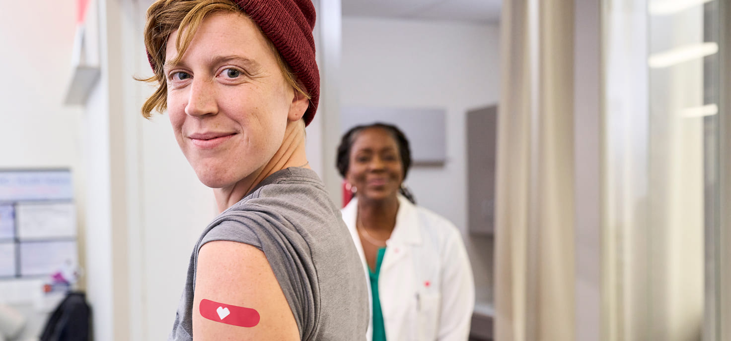 A person shows off the adhesive bandage on their arm after vaccination.