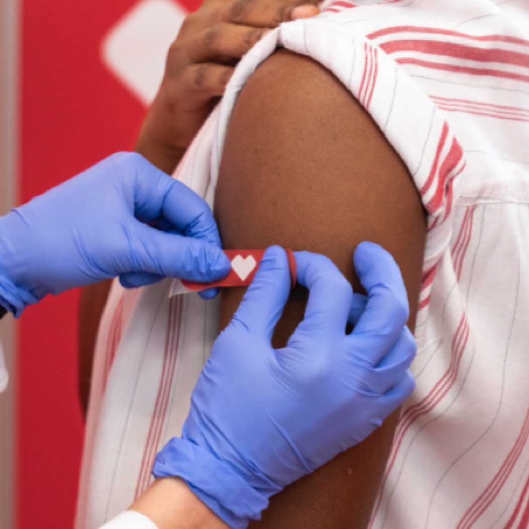 Arm of just-vaccinated person receiving CVS red bandage
