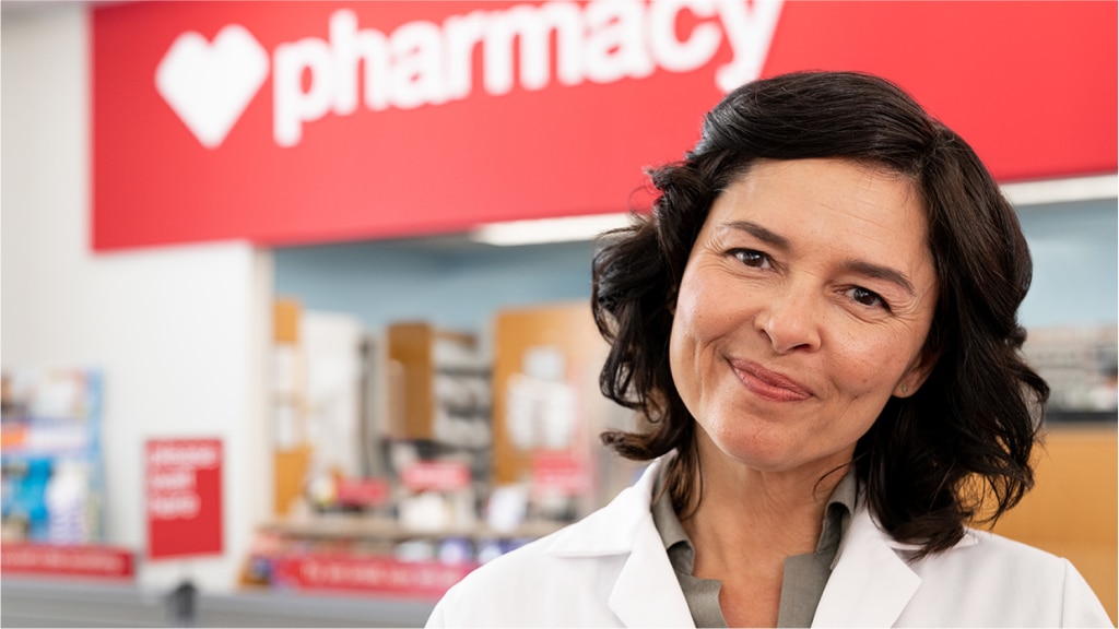 A certified immunizer at CVS stands in front of the pharmacy.