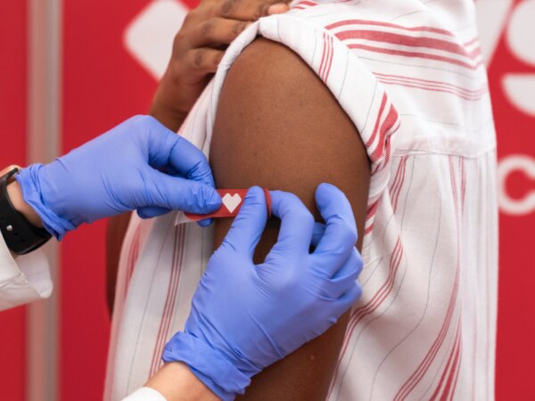 Arm of just-vaccinated person receiving CVS red bandage