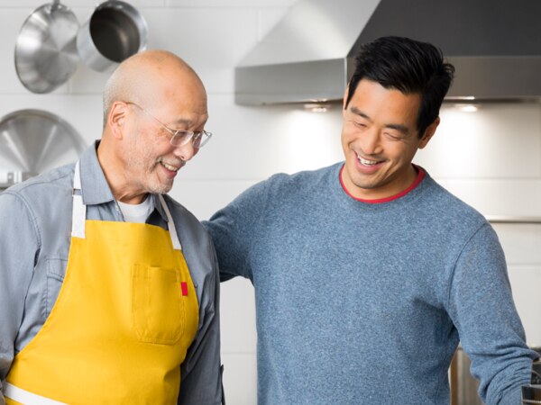 Padre e hijo adulto riendo en la cocina