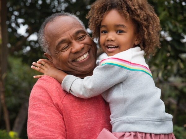 Hombre negro mayor abrazando a niña pequeña