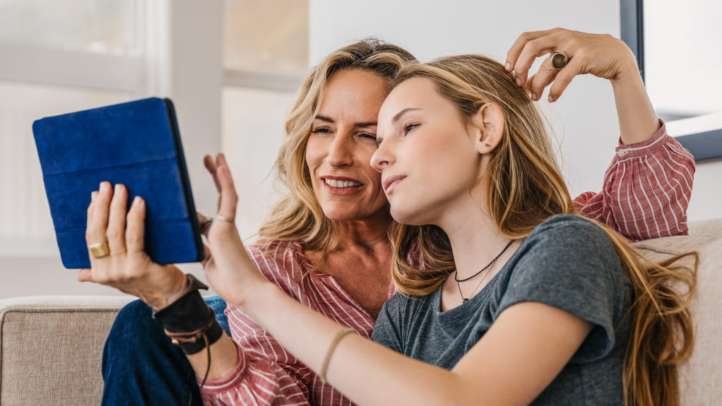 A couple sitting on the couch scroll through a tablet together to learn more about Tdap.