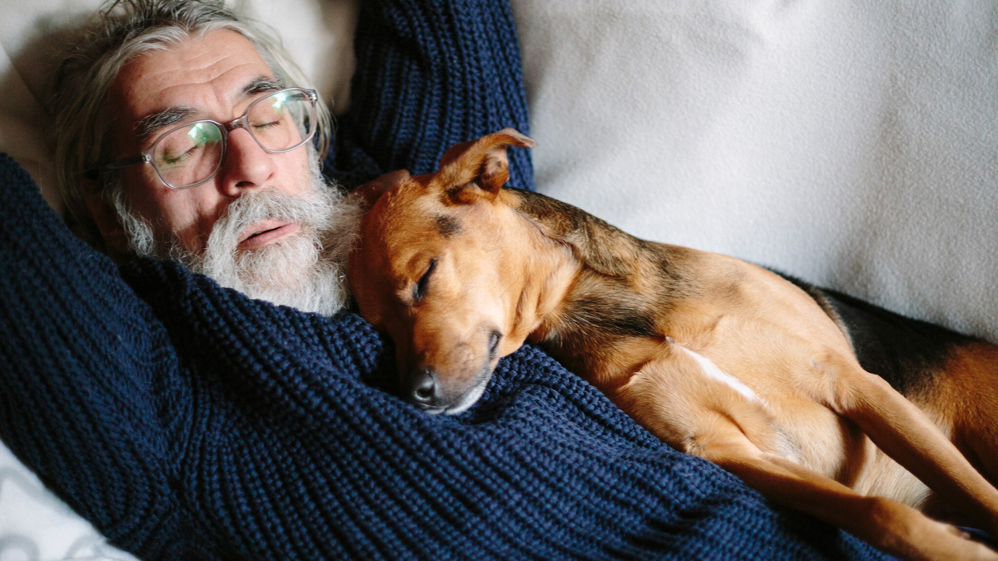 Mature man sleeping peacefully with his dog on his chest.