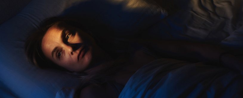 Person with insomnia lies in bed awake at night.