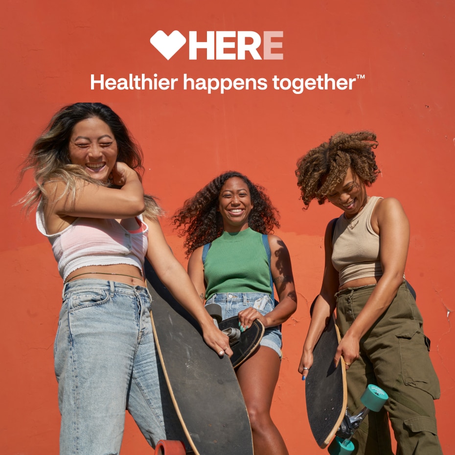 Three young women of color enjoy time skateboarding together. Here, healthier happens together.