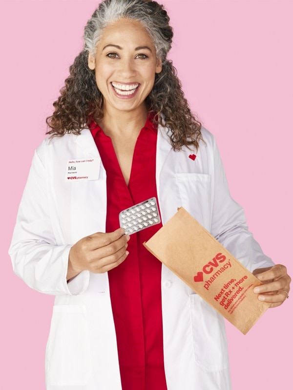 Profesional en farmaciade CVS® sacando un blíster de píldoras anticonceptivas de una bolsa de medicamentos con receta.