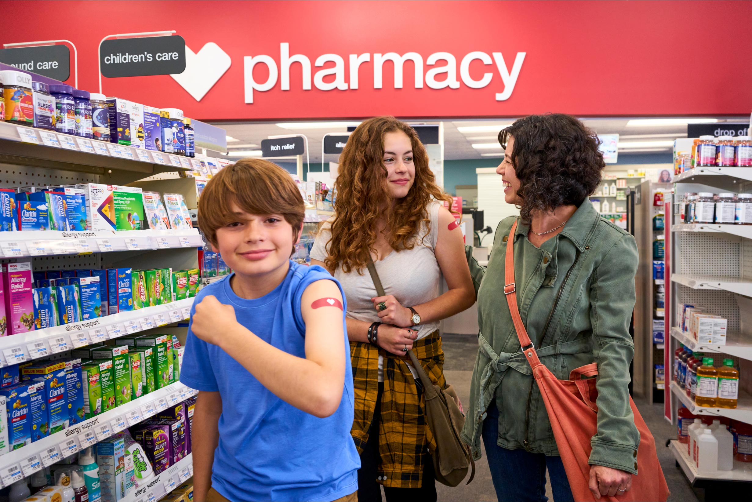 A child shows his vaccination bandage as he walks through a CVS aisle with his mother.