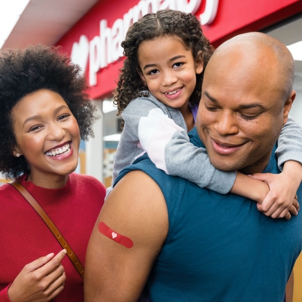 Familia feliz con apósitos rojos de CVS en el brazo luego de recibir vacunas contra la gripe