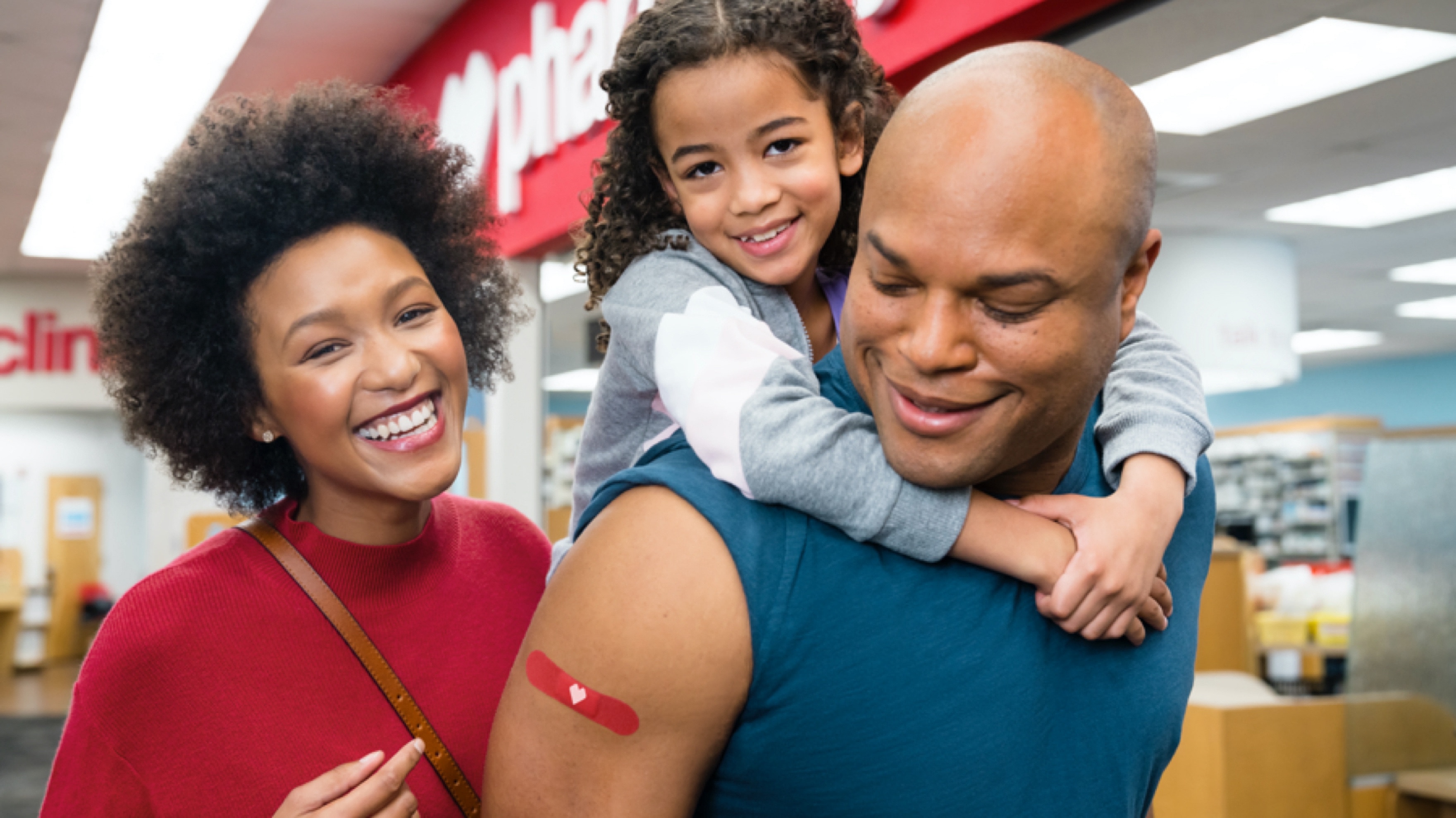 Happy family all with red CVS bandages on arms after receiving	flu shots