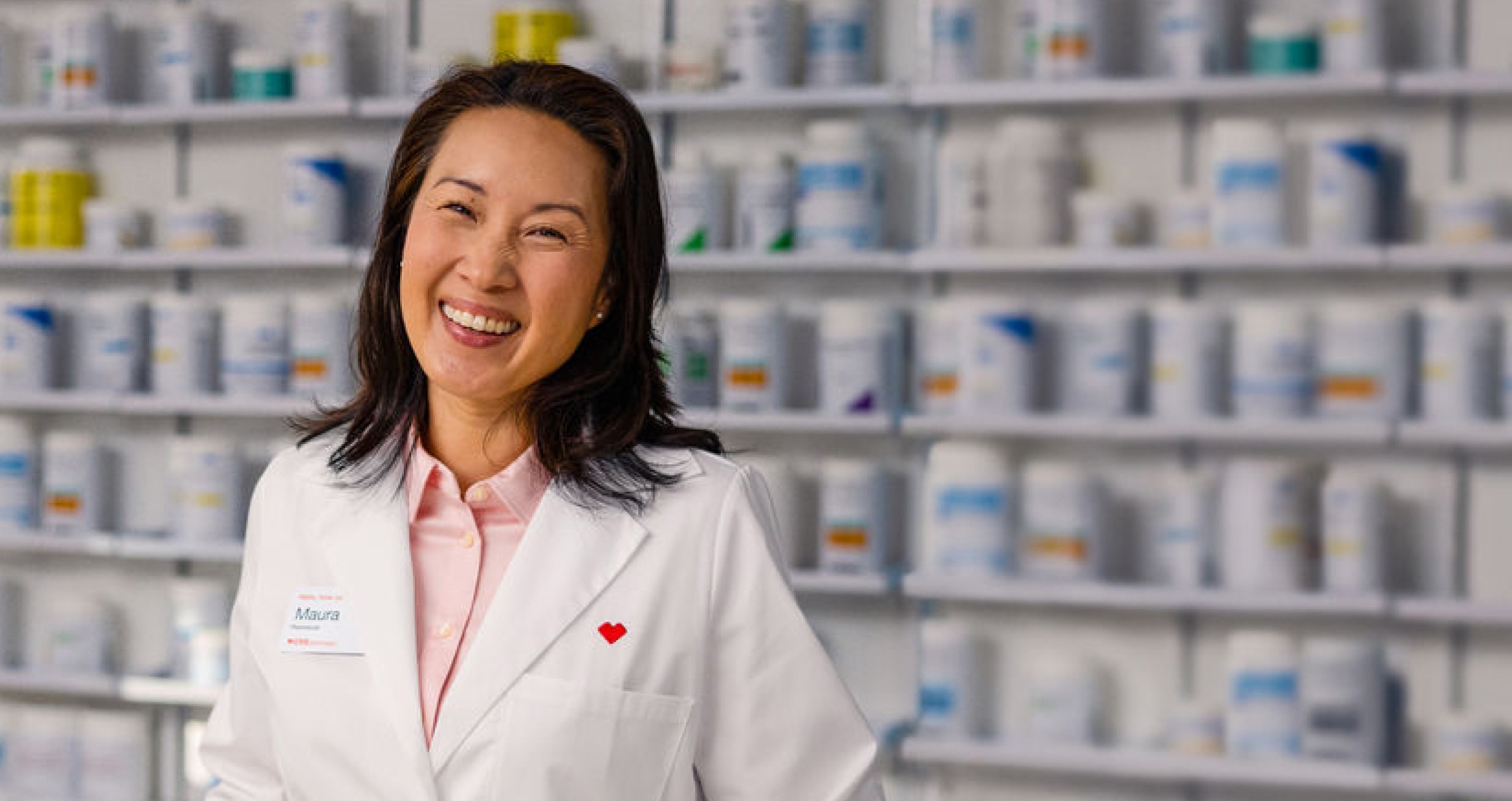 A smiling CVS pharmacist waits at the prescription counter.