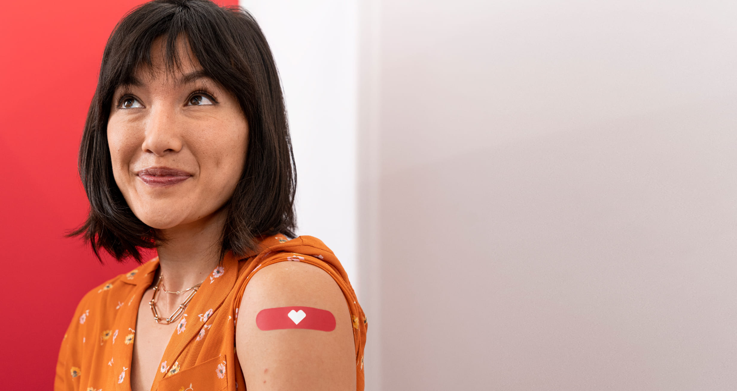 A smiling patient shows their bandaged arm after a vaccination.
