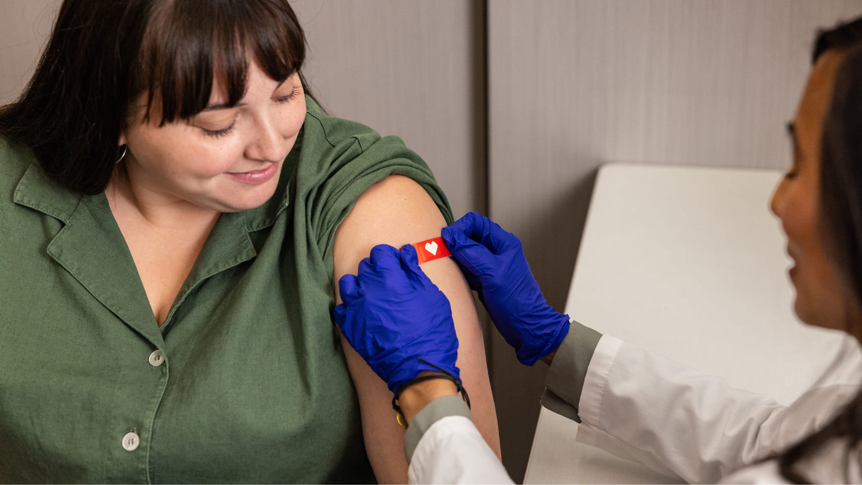 A provider places a bandage on a patient’s arm after vaccinating them.